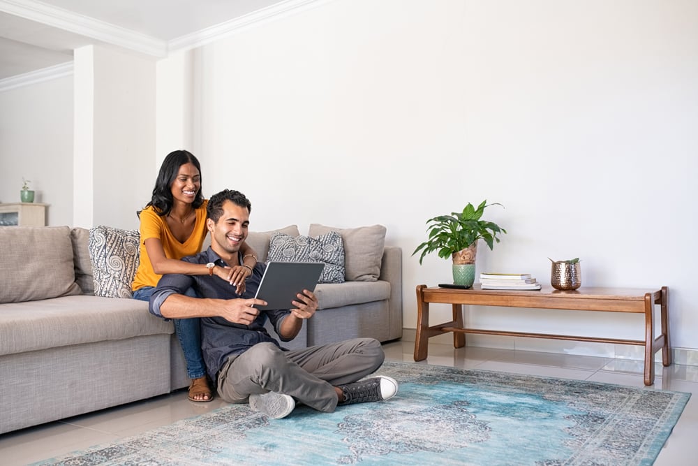 Happy couple looking at tablet in their living room