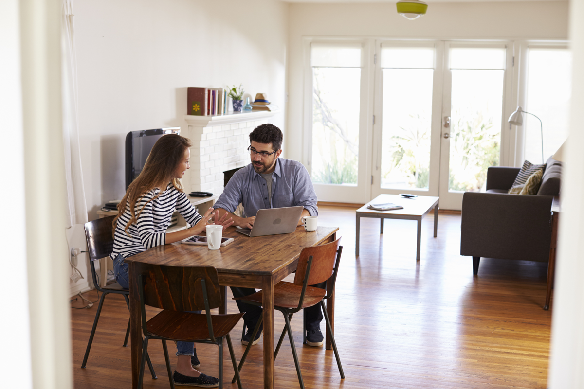 couple sitting at a table looking at a laptop