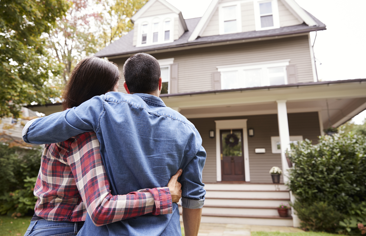 Pareja abrazándose mientras mira su hogar.